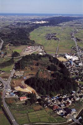 上空から千坊山遺跡(中央)と呉羽丘陵(後方)を見る